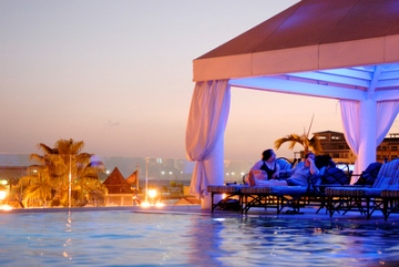 In de vooravond is het terras bij het zwembad van het Renaissance Hotel in Oranjestad met de luxe ligbedden en loveseats gehuld in een feeëriek licht. Een aangename spot om romantisch te borrelen.